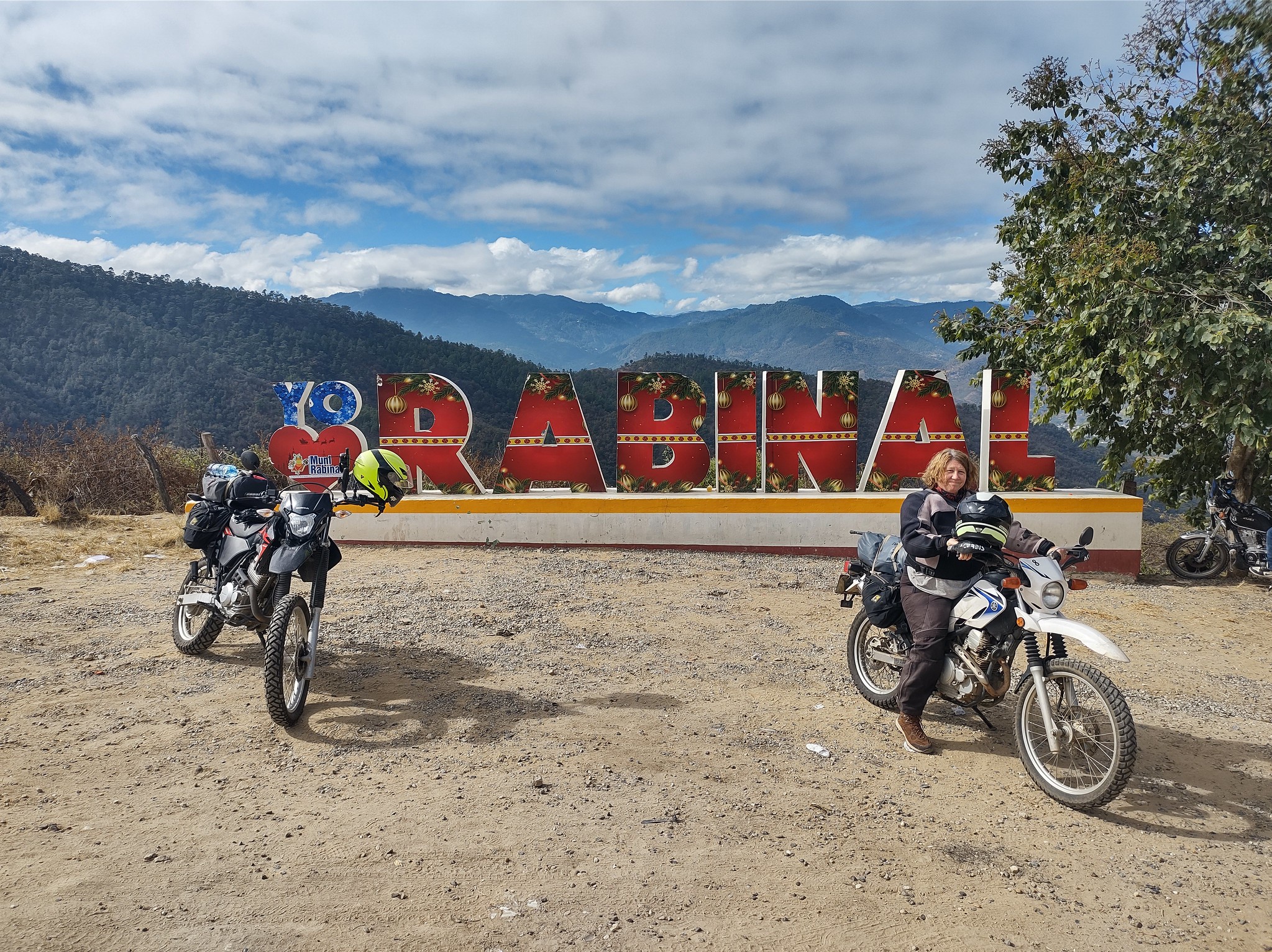 two motorcycles in front of
        a big sign that says Rabinal
