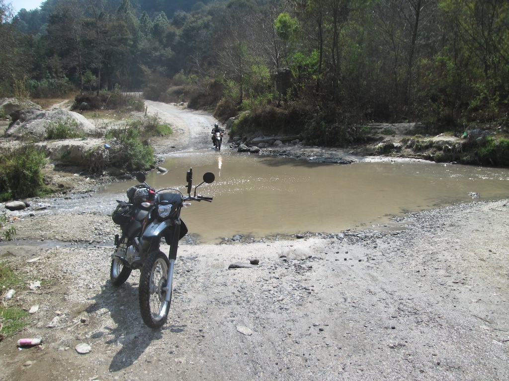 motorcycle begins crossing a river
            in shallow water
