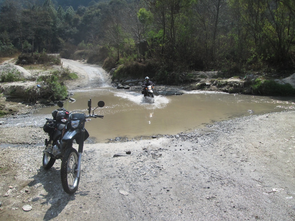 motorcycle
            begins crossing a river in shallow water