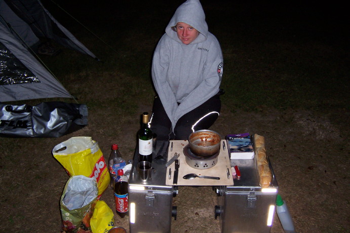 a
        woman sits at a pannier table and chairs and she is wearing a
        sweatshirt and she looks cold