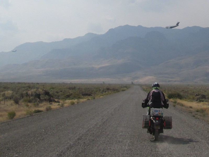 Coyotebroad attacked by planes Jayne riding her motorcycle with military transport planes in the distance.