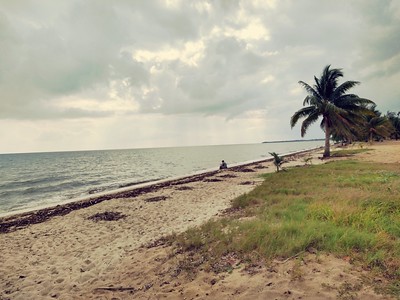 There is a lone woman sitting on the otherwise empty beach
        with the ocean.