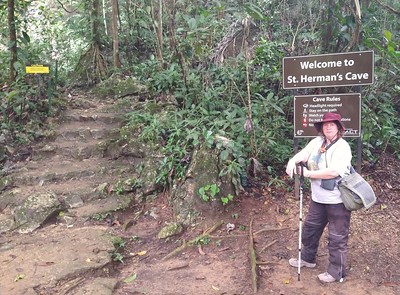 Me next to the
        sign for the entrance to a cave.