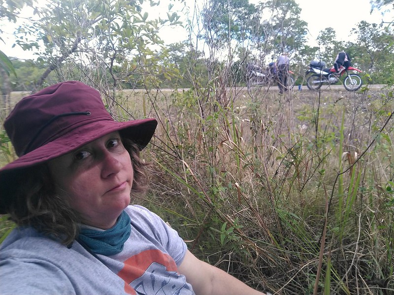 Jayne sitting in weeds with the motorcycles behind her on
        the road.