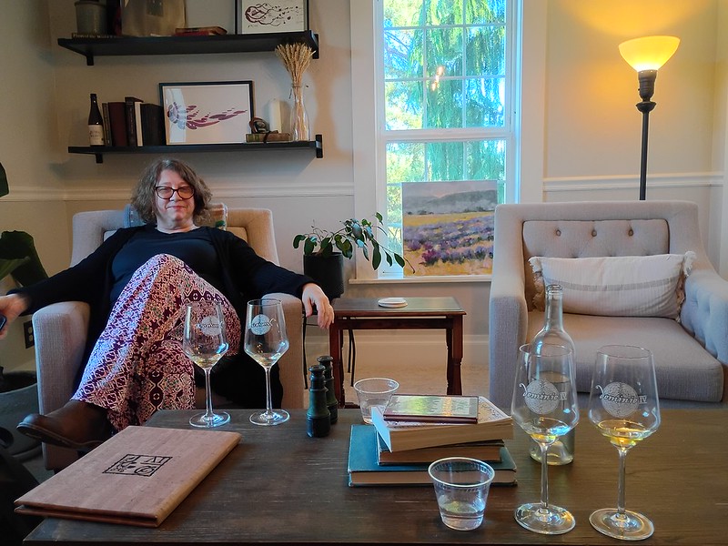 a woman sits comfortably in a room,
enjoying a glass of wine