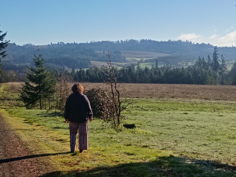 a woman is standing on a gravel road
looking out over a a picturesque valley
