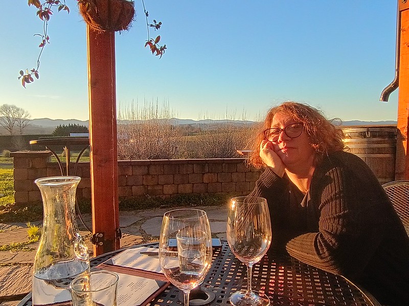 a woman sits at a table, lit by a
brilliant sunset