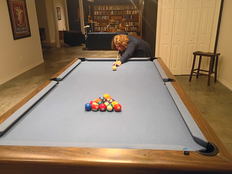 A woman is bent over, ready to break for
a game of pool