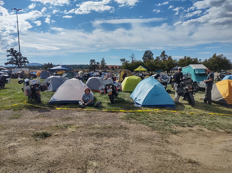 lots of tents all set up next to each other in a field with motorcycles interspersed between them