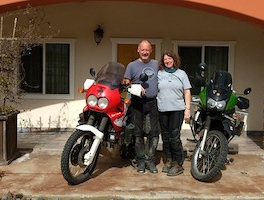 smiling couple standing between their motorcycles